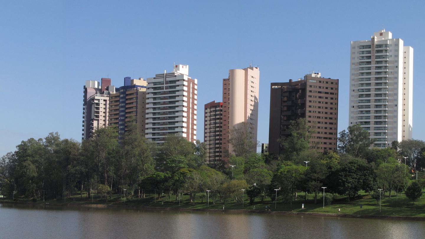 Lago Igapó em Londrina, com os prédios da orla atrás das árvores do parque
